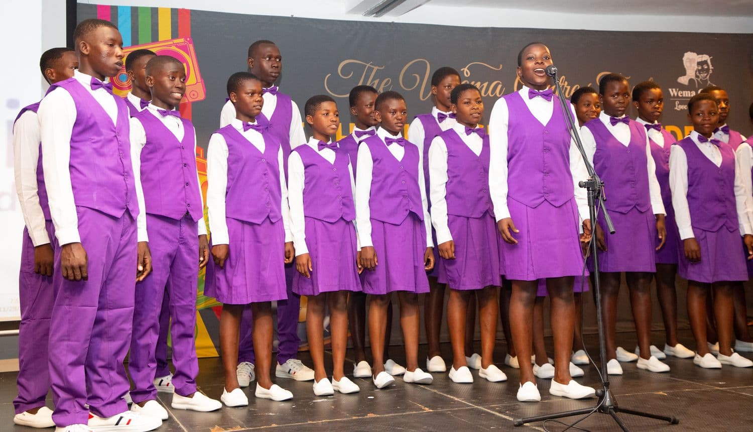 A Wema choir soloist sings into the microphone during a performance